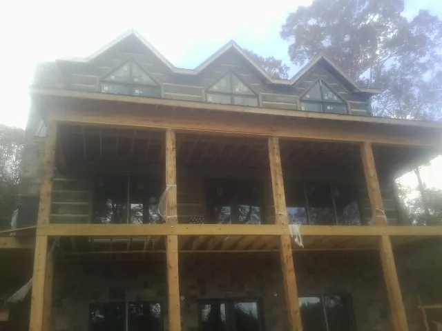 Dormers and porch framing on a large log home under construction — Roof Coating work by our crew in Polo